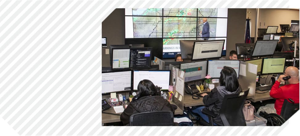 Diagonal grey stripes as a background with an image of three Syfan employees working on automotive parts logistics at computers with multiple screens.