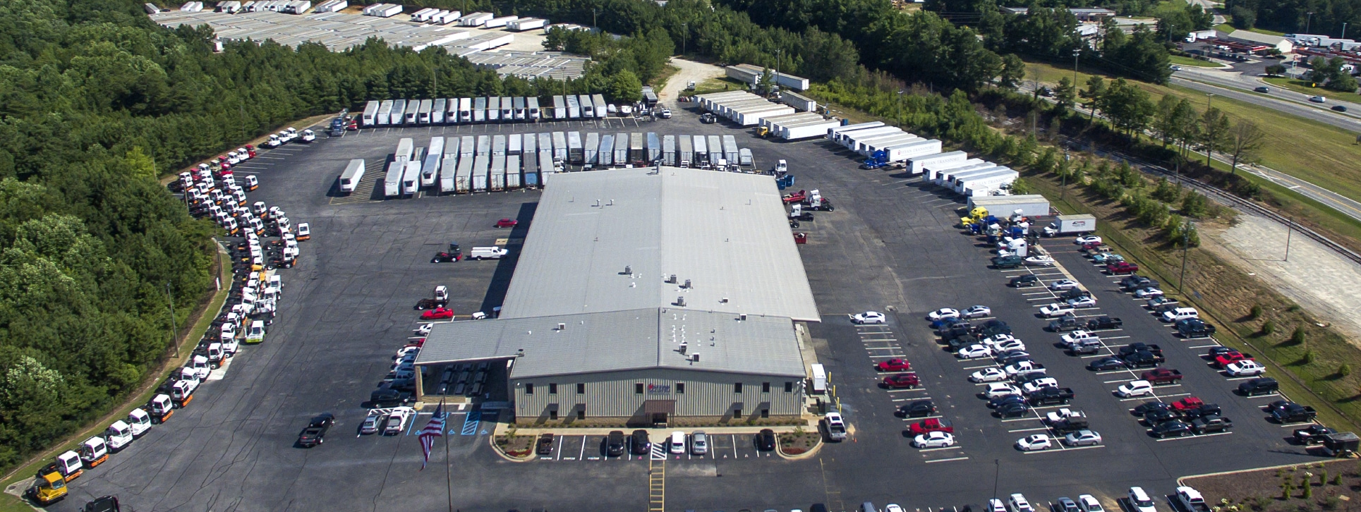 Aerial view of the Syfan Logistics Headquarters building and parking lot full of terminal tractors, tractor trailers, and cars.
